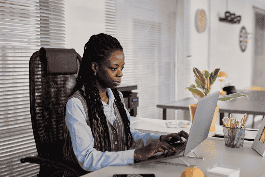 Woman working on a laptop in an office while researching ETF vs index fund options for beginner investing and financial planning