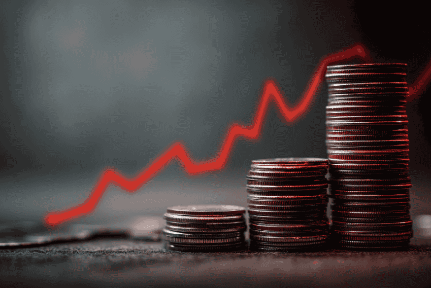 Increasing stacks of coins with an upward red line showing how consistent budgeting grows wealth over time