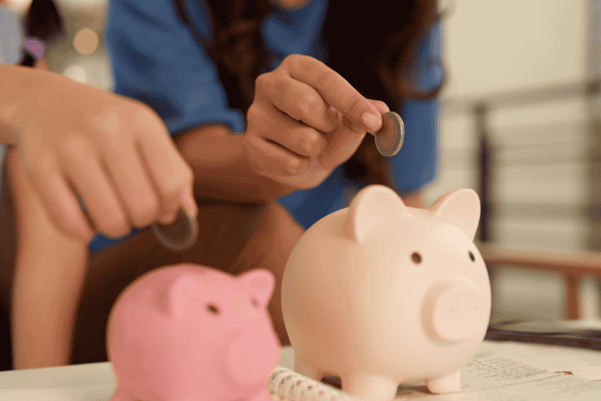 Family putting coins into piggy banks to save for long-term financial goals