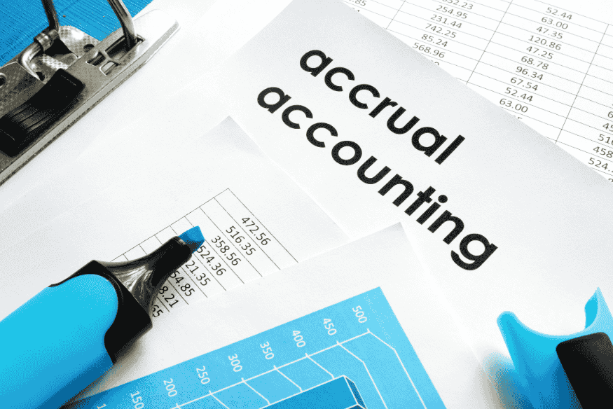 Accrual accounting documents with spreadsheets and highlighter on a desk