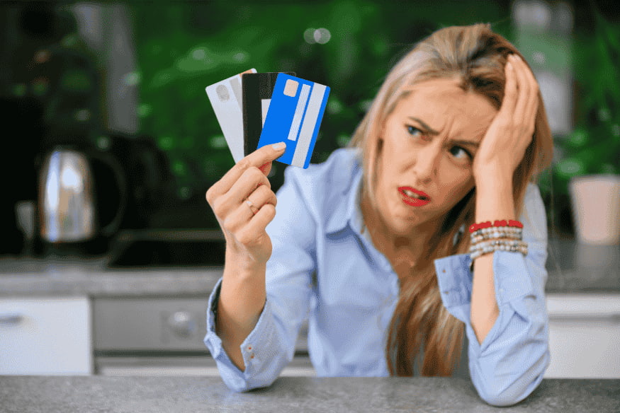 Worried woman holding several credit cards and feeling overwhelmed by high-interest debt.