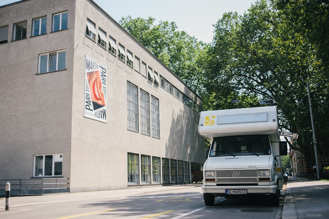 white ford van parked beside gray concrete building during daytime