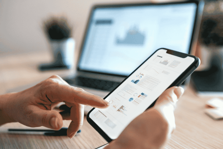 Person using a smartphone to check financial charts and manage money with digital tools.