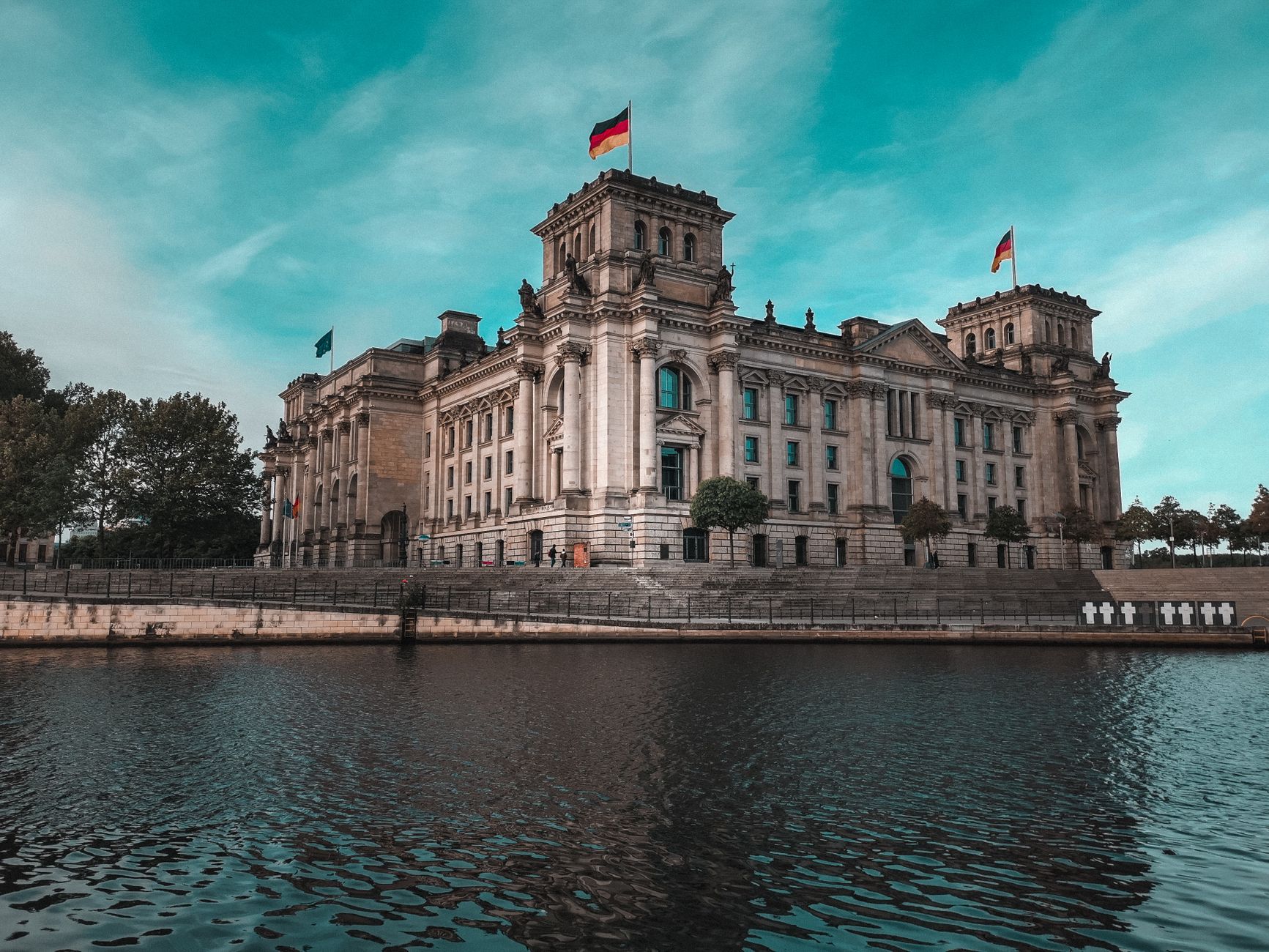 Stunning view of the Reichstag in Berlin beside the river, showcasing its architectural magnificence.