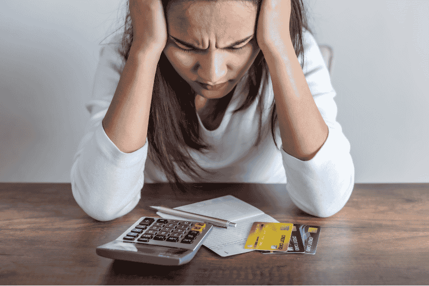 Worried woman looking at bills, calculator and credit cards, concerned about credit card debt.