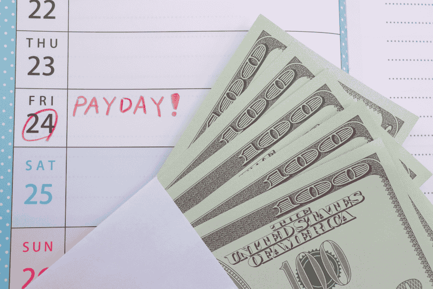 Notebook with payday marked and cash placed on top.