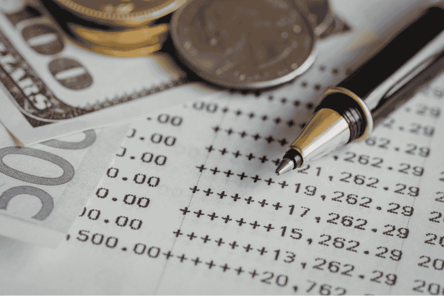 Close-up of bank statement, cash, and pen used to track transactions for a monthly budget plan