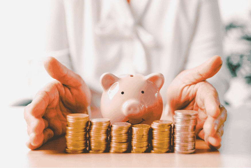 Person protecting a piggy bank surrounded by stacked coins representing long-term savings.