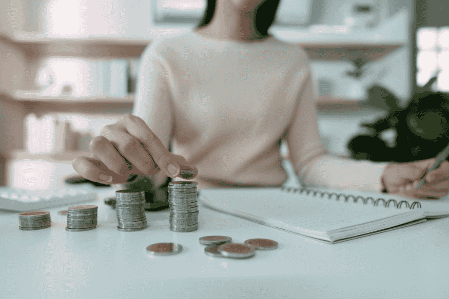 Woman stacking coins and taking notes to track savings and improve personal financial health