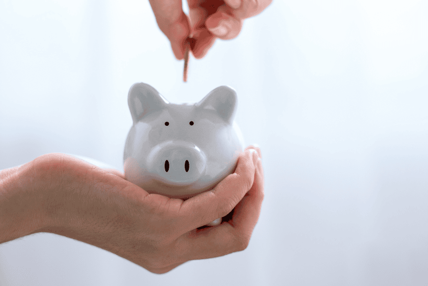Person putting a coin into a piggy bank to build an emergency savings fund for the business