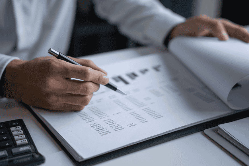 Person reviewing financial documents and analyzing numbers for setting realistic financial goals.