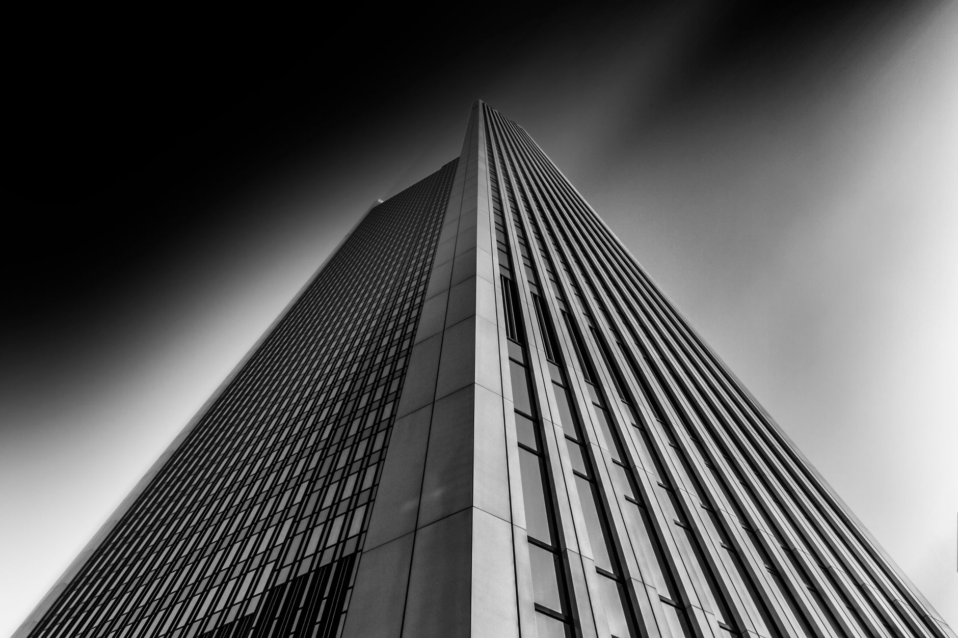 Low angle capture of a modern skyscraper in Frankfurt, showcasing contemporary architecture in monochrome.
