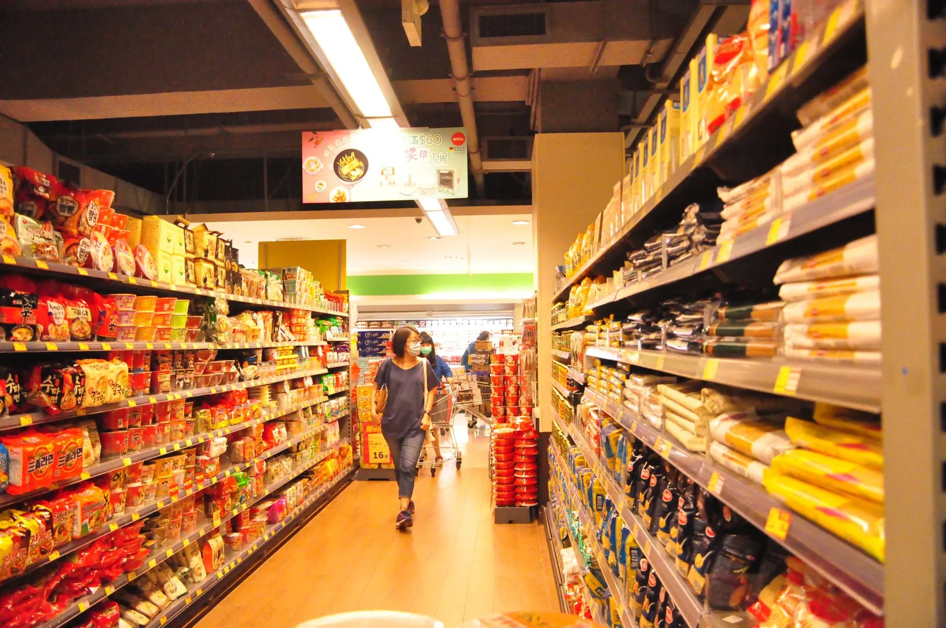 Shelves with assorted food products and customers choosing food while walking in protective masks