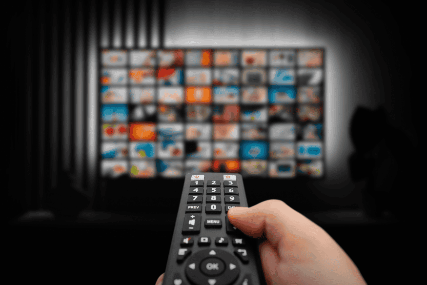 Person using a remote to manage streaming subscriptions and cut recurring bills
