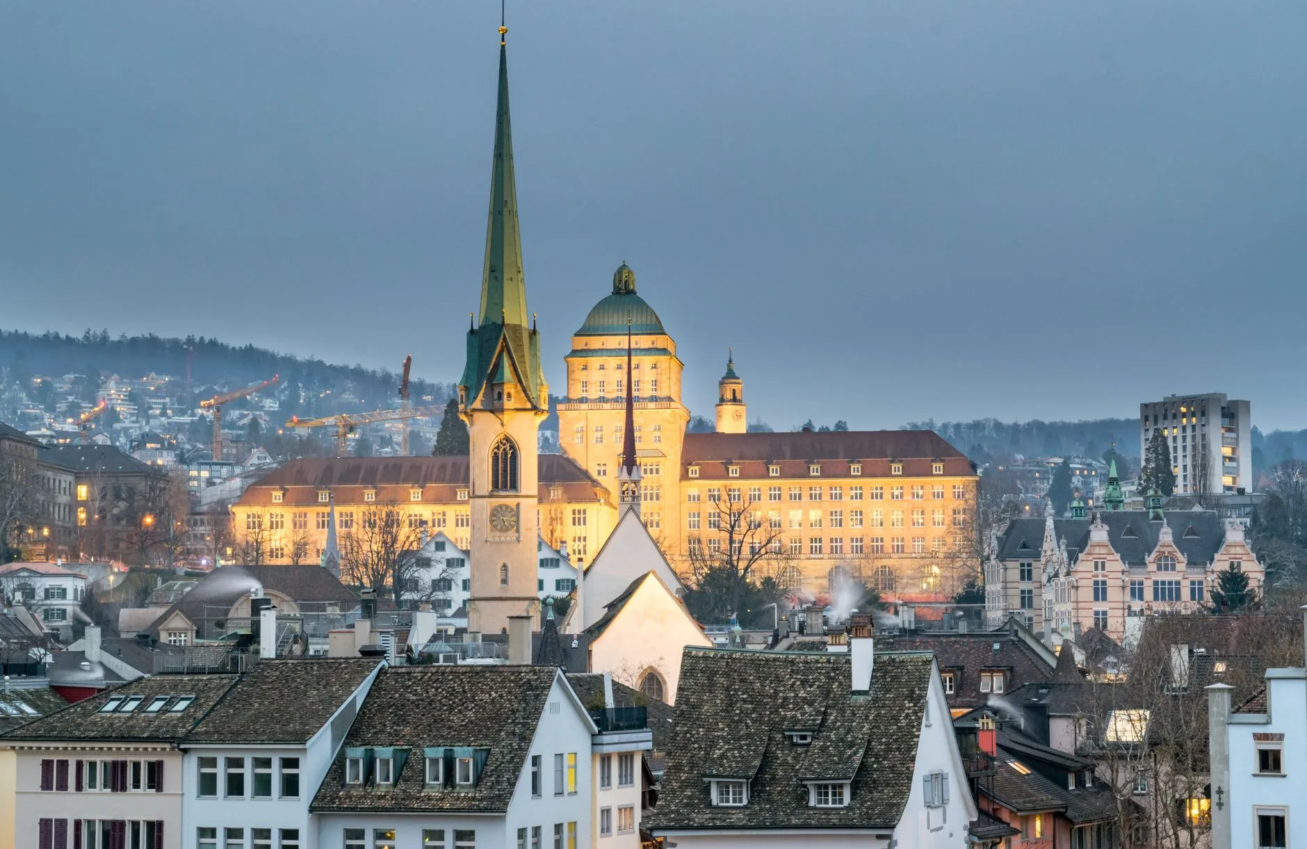 A stunning aerial view of Zurich showcasing the iconic Predigerkirche and urban landscape at twilight.