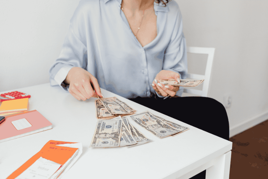 Woman organizing cash on a desk as part of budgeting using the 50/30/20 rule.