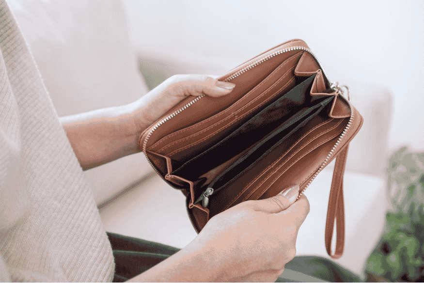 Close-up of hands holding an open empty wallet, symbolizing the long-term financial impact of overspending.