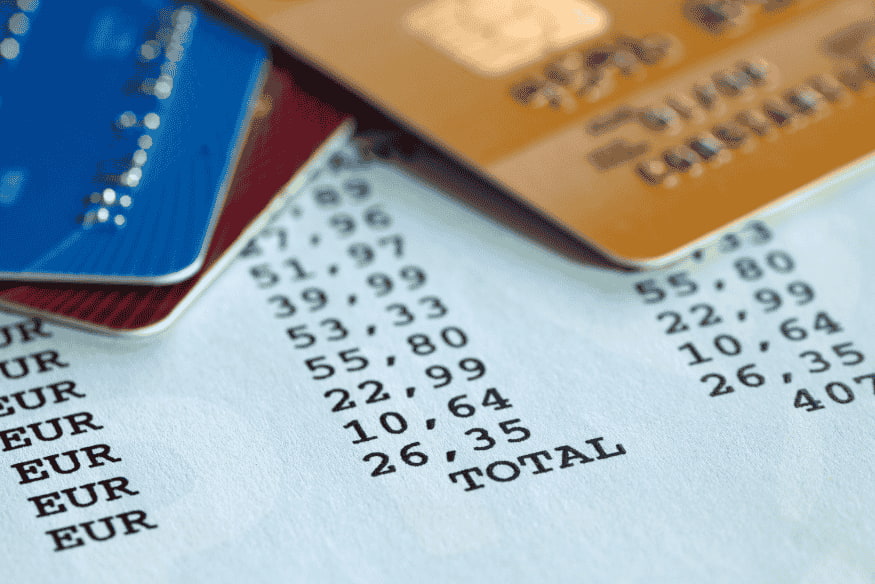 Several credit cards placed on a printed receipt listing euro amounts and a total.